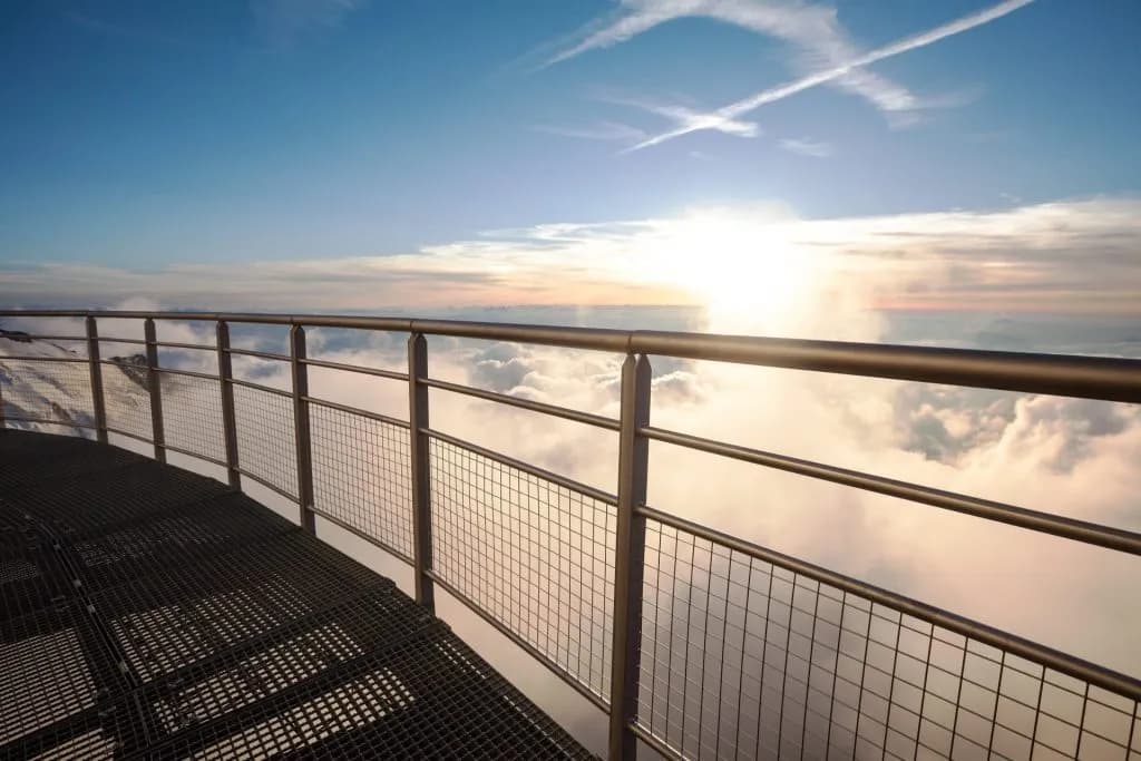 Panoramic deck railing above clouds at sunset, view from Gouter Hut.