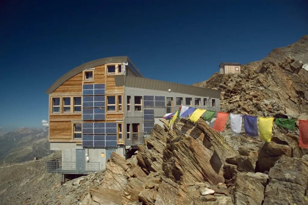 Tête Rousse Hut with solar panels nestled in rocky alpine terrain under a clear blue sky