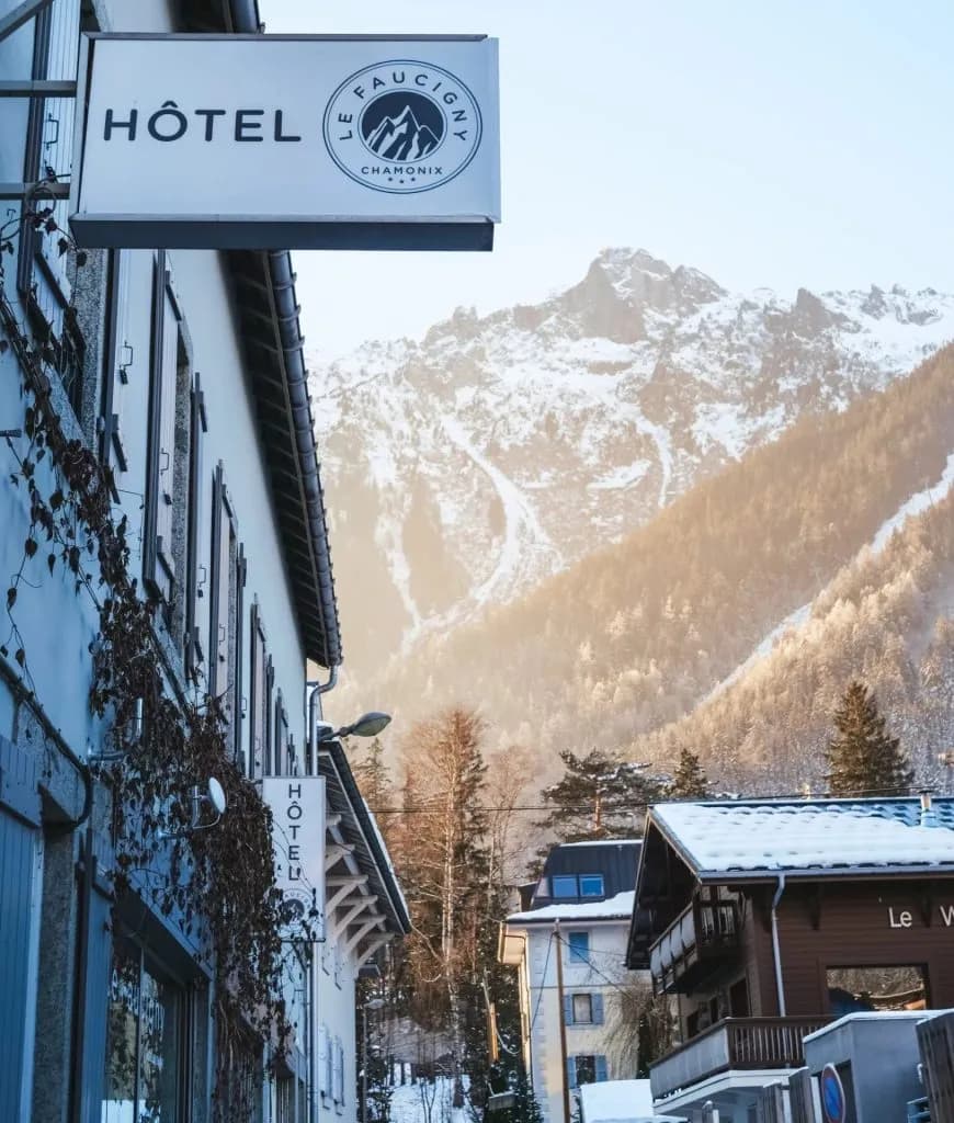 Hotel Le Faucigny sign in Chamonix street with snow-covered alpine mountain background