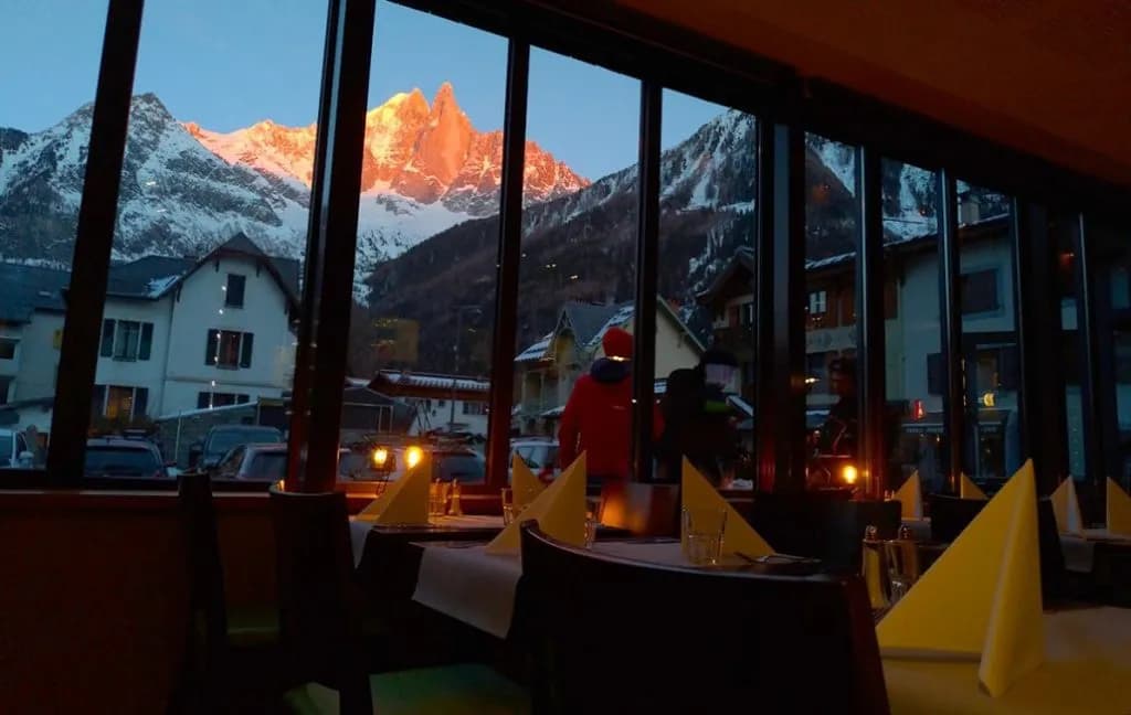 Restaurant dining room view of snow-capped mountains glowing at sunset in Les Lanchers.