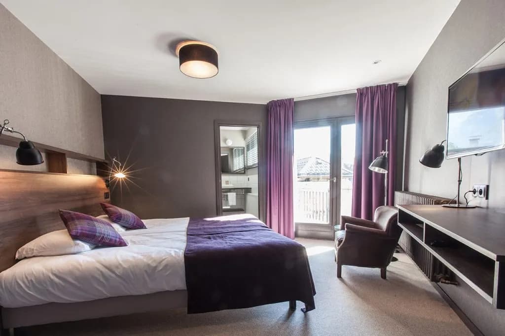 Double room with purple accents, wooden headboard, and balcony access, Isabelle hotel.