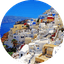 White buildings with blue domes on the cliffs of Oia, Santorini overlooking the Aegean Sea.